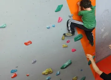 A kid climbing a wall manufactured by oxo